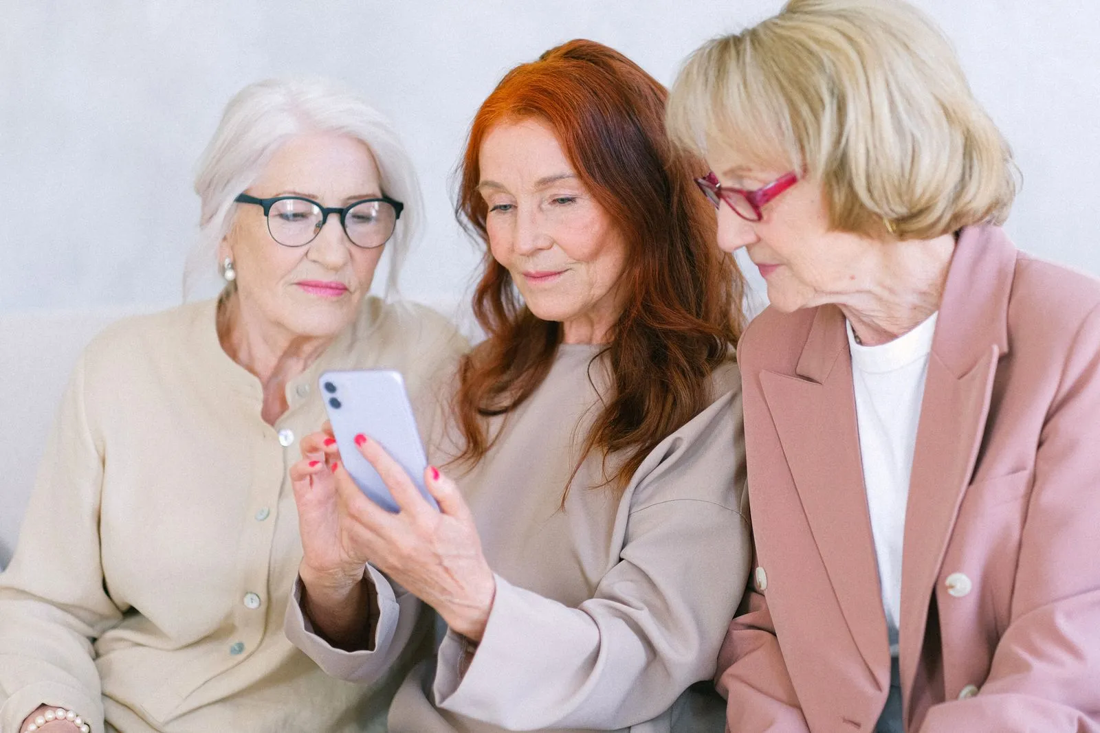 Three women sitting together and looking at a smartphone.